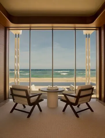 Beachfront casita at Amanvari with two wooden chairs facing expansive ocean views through floor-to-ceiling windows.