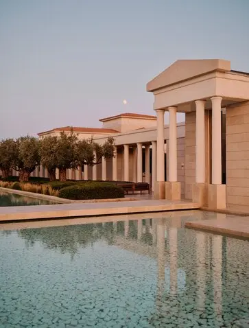 Amanzoe's terracotta pavilions line a reflecting pool at dawn in Greece.